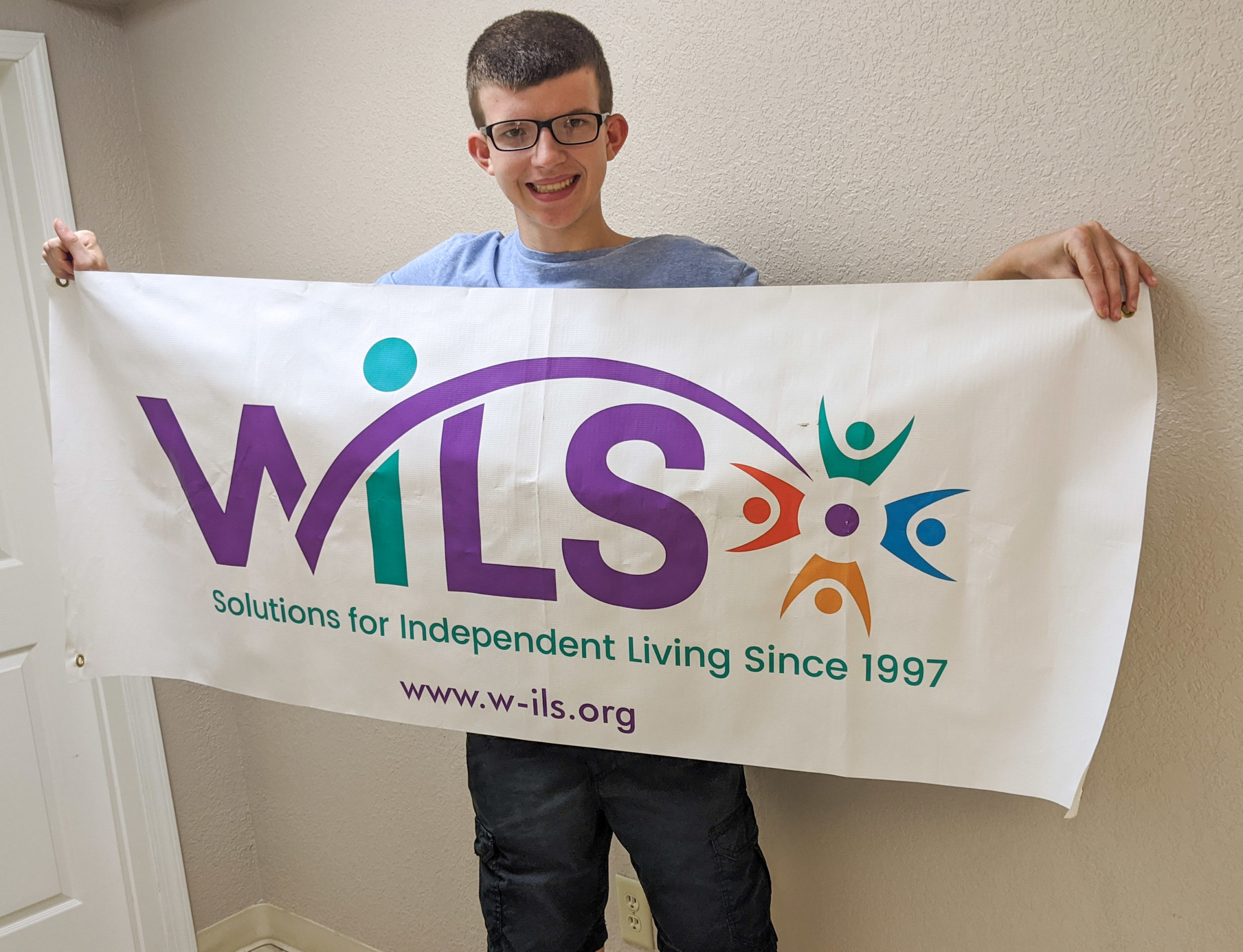 Young man stands holding WILS banner