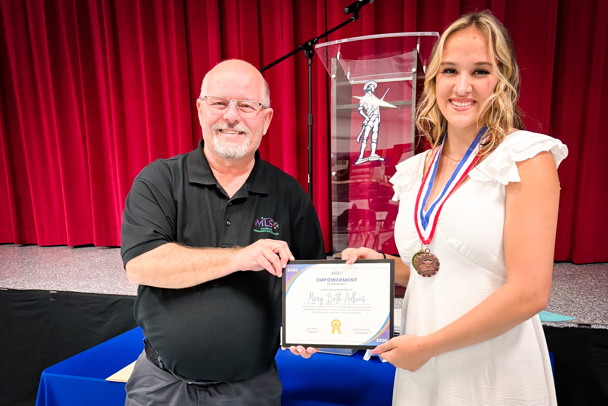 WILS staff member Don on left and Scholarship winner, Mary Beth on the right hold scholarship certificate between them.