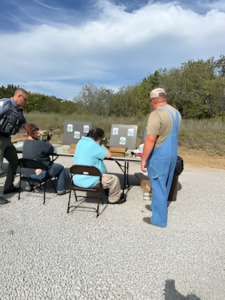 group of people with their backs to the camera shooting at paper targets.