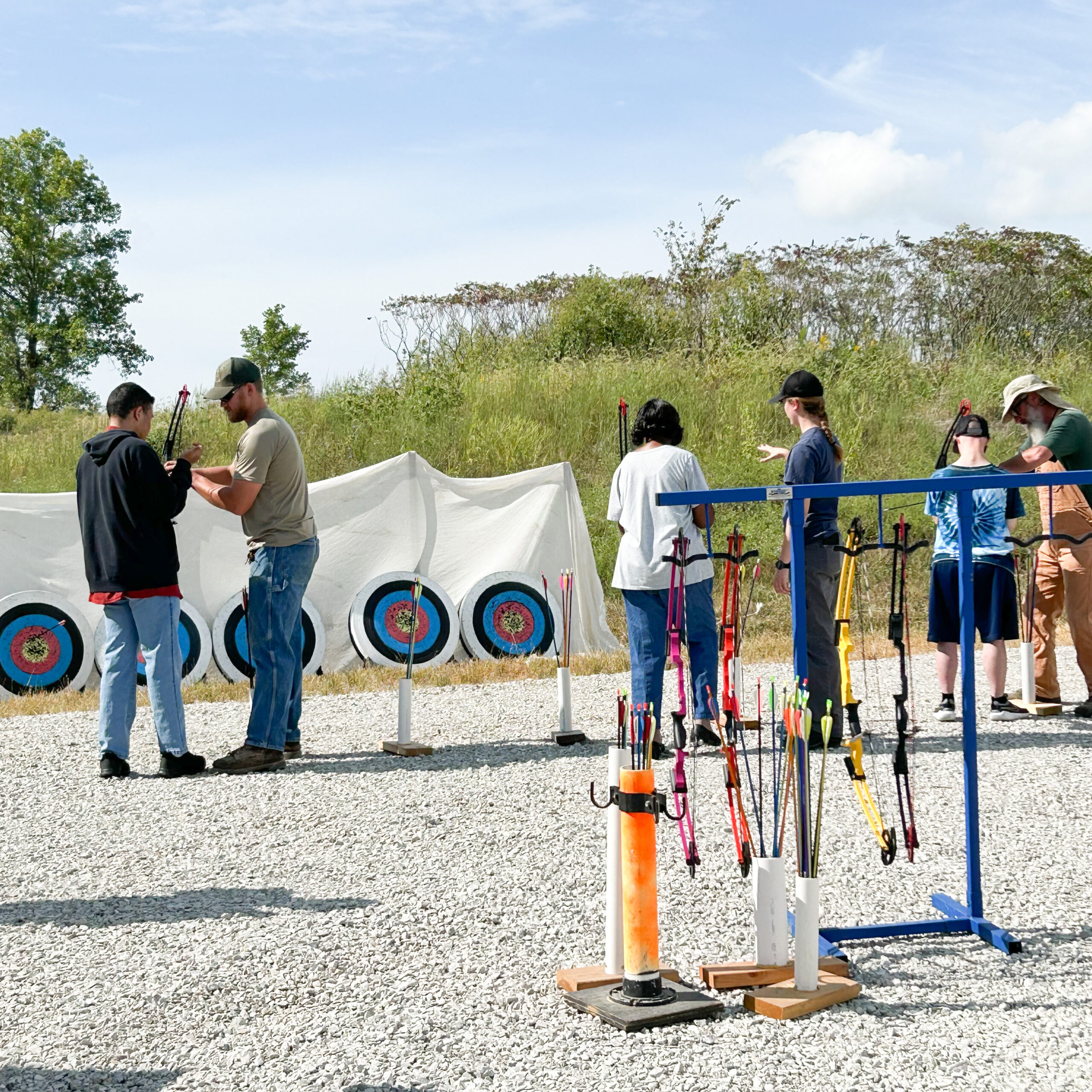 Group of people with their backs to the camera practice archery.