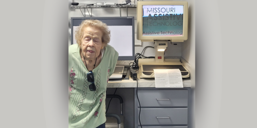 Women wearing a green shirt stands beside a magnifyer.